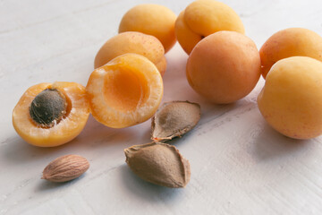 Apricots and kernel on white wooden background. Apricot seeds.