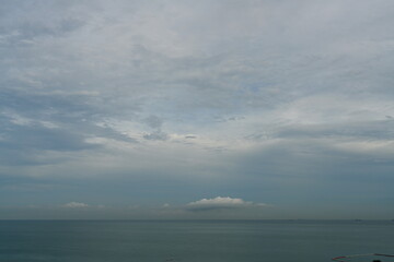 The evening atmosphere of the sea has few waves. Scattered clouds, no sunlight, calm sea, light gray clouds in the rainy season.
