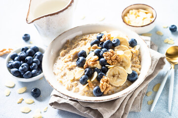 Oatmeal porrige with berries and nuts in craft bowl at white background. Healthy breakfast.