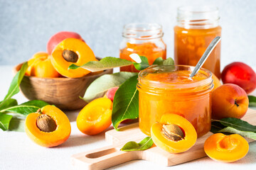 Apricot jam in glass jar, homemade preservation at white kitchen table.