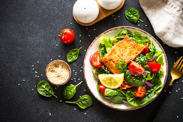 Green salad with salmon fillet. Healthy lunch, diet nutrition. Top view on black.