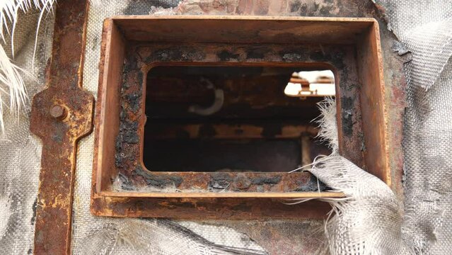 View of the window of a rusty military vehicle. Burnt military equipment