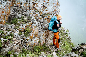 Fototapeta premium The guy climbed the rock alone, mountain hiking extreme sport, hard climbing, hiking with a backpack in the mountains, trekking