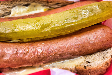 Closeup of a hot dog with pickle and cheese.