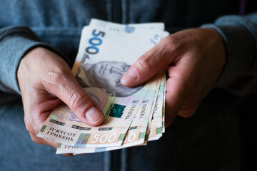 White female shows Ukrainian hryvnia bills in her hands