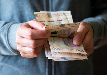 White female count Ukrainian hryvnia five hundred bills in her hands