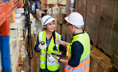 Asian male and female warehouse worker checking order stock. Professional industrial warehouse team working at store workplace. Unity and teamwork concept.