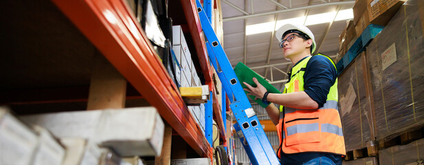 Portrait handsome Asian male warehouse professional worker in safety vest and hardhat helmet in...
