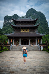 Mujer turista adentrándose a templo budista, en losa alrededores de Ninh Binh, Vietnam	