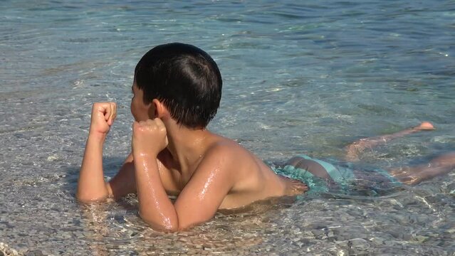 Kas, Turkey - 2nd of July 2022: 4K Child rubs his irritated eyes after diving in salty waters
