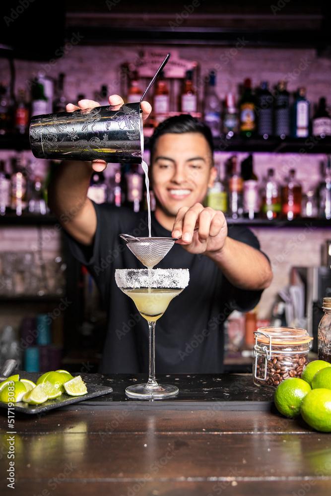 Wall mural Latin American cocktail maker straining a drink to prepare a cocktail in a nightclub