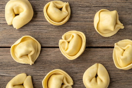 Uncooked cappelletti or tortellini over wooden table