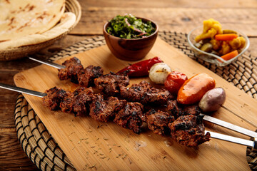 Shish Kebab or beef seekh boti served in a wooden cutting board isolated on wooden background side...
