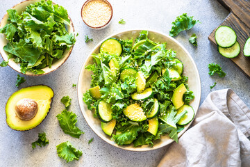 Green salad, vegan meal. Kale salad leaves with cucumber and avocado. Top view.