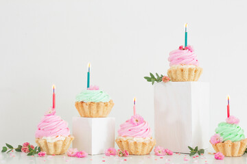 pink and green cupcakes with spring flowers  on wooden podiums on white  background