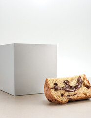 Slice of chocolate filled panettone, with a white box behind, isolated on white