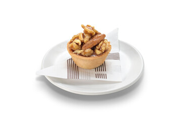 Nuts tartlet on a white ceramic plate, isolated on white