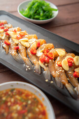 Prawns pickled in soy sauce or shoyu sauce and sprinkled with chili and sliced garlic with spicy sauce Seaweed and Japanese rice are side dishes on a brown wooden table.