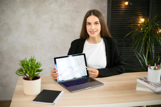 Girl shows on graphic on laptop in office