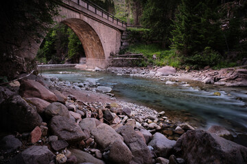 Fototapeta na wymiar bridge with river in the lake of paneveggio trentino alto adige