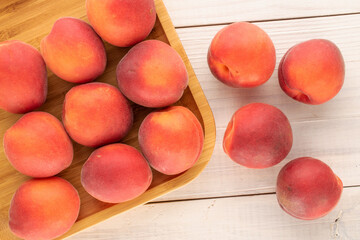 Several sweet red apricots with a bamboo tray on a wooden table, close-up, top view.