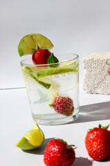 Carbonated drink with lime slices and strawberries in glasses decorated with mint leaves