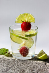 Carbonated drink with lime slices and strawberries in glasses decorated with mint leaves