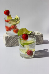 Carbonated drink with lime slices and strawberries in glasses decorated with mint leaves