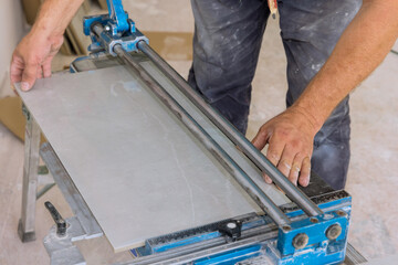 Using manual tools equipment, a construction worker cuts the ceramic tile using manual tools for laying ceramic tiles in place