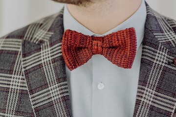 Closeup of a male wearing red bow tie and checkered gray blazer