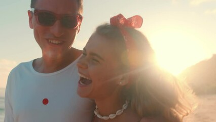 Young cheerful Caucasian tourist couple man and woman lovers walk along ocean embracing each other and laugh remembering how they met and first date located on resort sea island. Love, romance