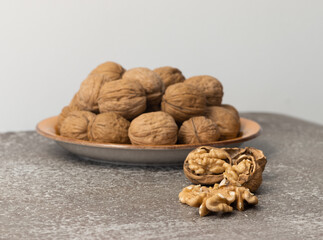 Plate with whole walnuts and shells on wooden table