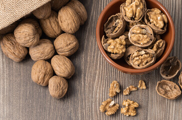 walnuts out of the sack and in the plate whole, shells on the wooden table