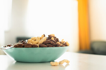 Bowl of cereals in bright kitchen on white table in green plate for kids breakfast before school