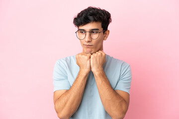 Young Argentinian man isolated on pink background With glasses and tired