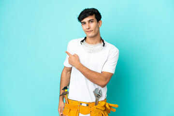 Young electrician Argentinian man isolated on blue background pointing back