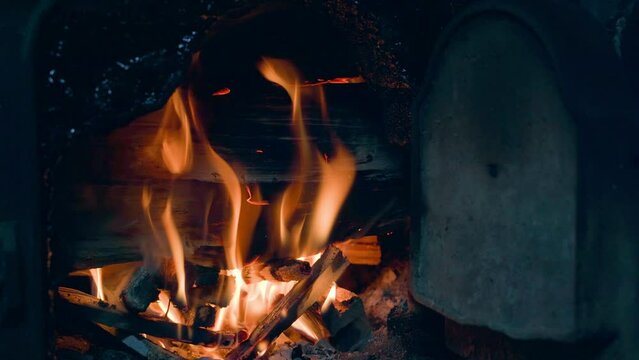 Fire burns in the open firebox of a wood-burning boiler close-up