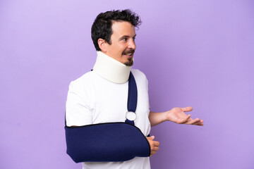 Young caucasian man wearing a sling and neck brace isolated on purple background with surprise...