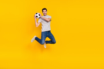 Fototapeta na wymiar Full length body size view of attractive cheerful guy jumping throwing ball isolated over bright yellow color background