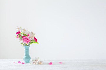 pink and white flowers in blue vase on white background