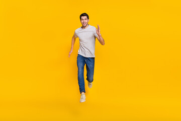 Fototapeta na wymiar Full length body size view of attractive cheerful sportive guy jumping running isolated over bright yellow color background