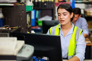 Asian Indian beautiful woman warehouse worker checking order  in desktop computer at office...