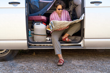 senior woman on a camper van cheking map with sunglasses