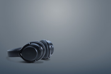 Computer headphones. Black headphones on a dark grey  background. The concept of listening to music, creating audio, music. Computer work, abstraction and minimalist style.