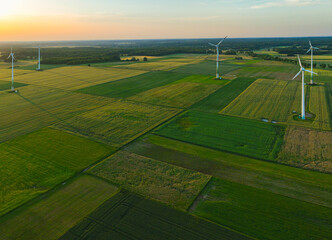 Obraz premium Aerial drone view of wind power turbines, part of a wind farm. Wind turbines on green field in countryside. Wind power plant.