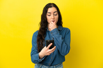 Naklejka premium Young caucasian woman isolated on yellow background thinking and sending a message