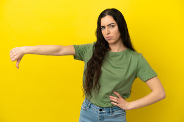 Young caucasian woman isolated on yellow background showing thumb down with negative expression