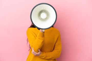 Young caucasian woman isolated on pink background shouting through a megaphone to announce something