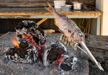 Malaga style of preparation of fresh fish, catch of the day, on skewers and open flame on fireplace with olive trees wood