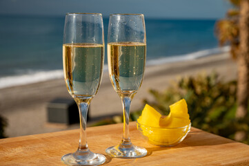 Outdoor breakfast with Spanish cava sparkling wine and pineapple with view on blue sea and sandy beach in Marbella, Costa del Sol vacation destination, Andalusia, Spain